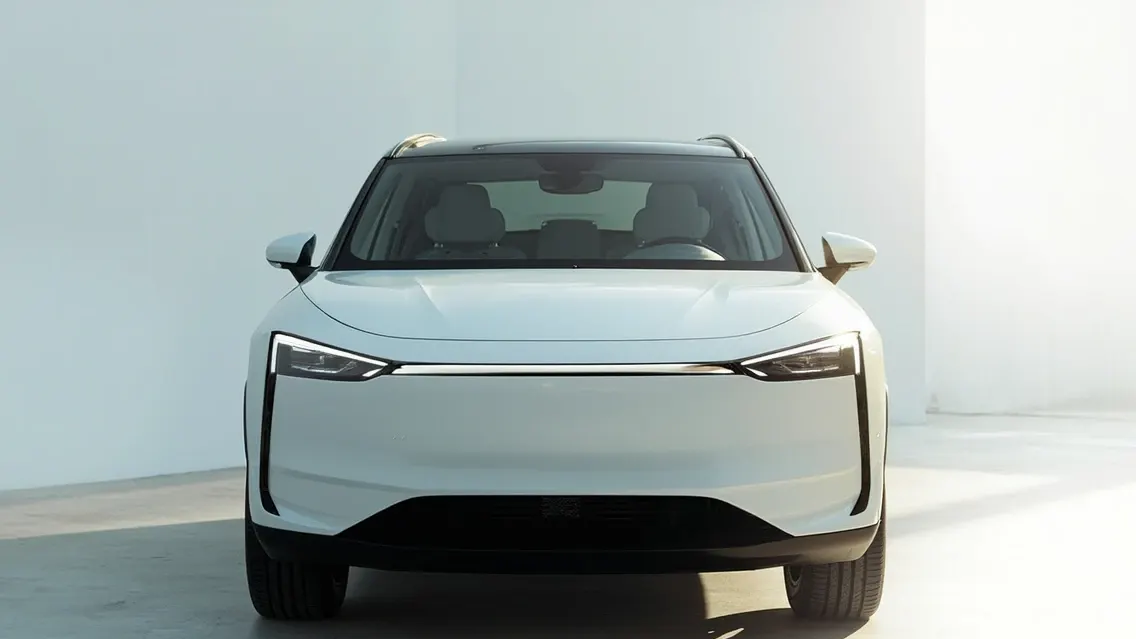 The front of a white 2025 Tesla Model Y Juniper in a bright studio